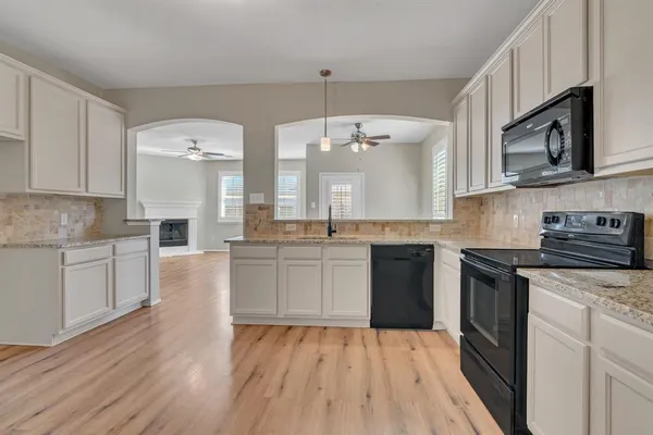 a kitchen with stainless steel appliances granite countertop a sink and cabinets with wooden floor