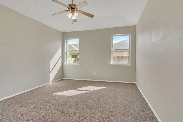 an empty room with windows and fan