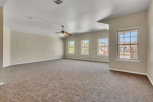 an empty room with windows and chandelier fan
