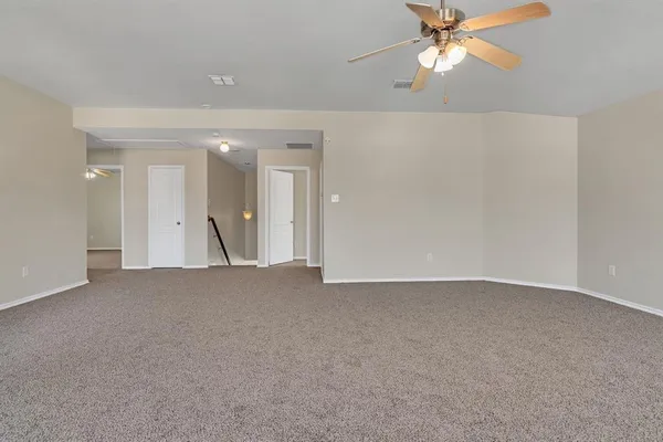 a view of an empty room and a chandelier fan
