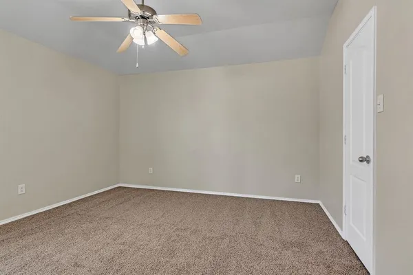 an empty room with a chandelier fan and windows