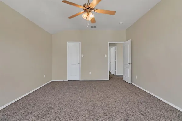 a view of an empty room and chandelier fan