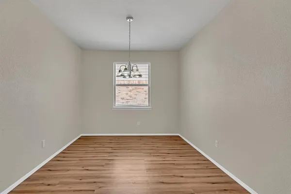 a view of empty room with wooden floor fan and window