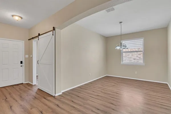 an empty room with wooden floor a ceiling fan and windows