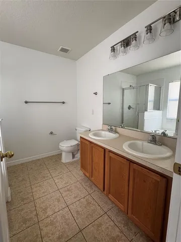 a spacious bathroom with a granite countertop sink a toilet and a mirror