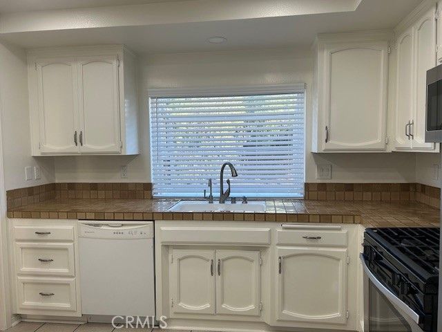 a kitchen with granite countertop white cabinets and stainless steel appliances