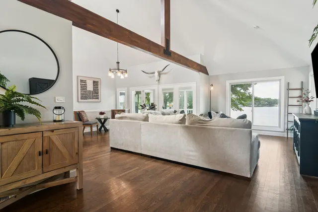 a living room with furniture a large window and wooden floor