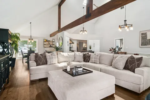 a living room with furniture kitchen view and a chandelier