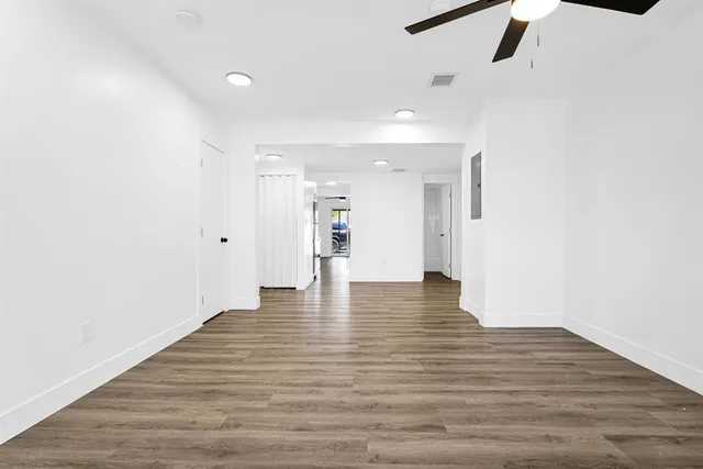a view of an empty room with wooden floor and stairs