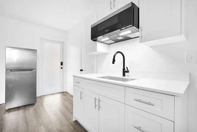 a kitchen with stainless steel appliances a sink a microwave a refrigerator and cabinets