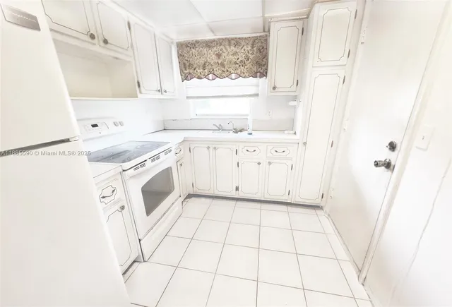 a kitchen with granite countertop white cabinets and white appliances