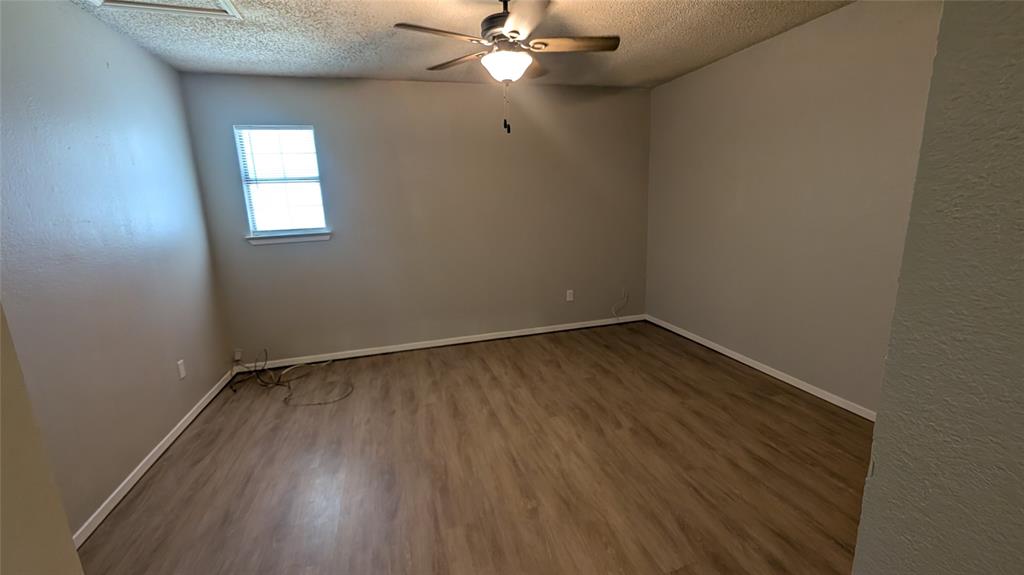 107 Beck Street, Unit B Florence, TX 76527 - Photo 4 of 8 A quiet bedroom featuring hardwood flooring and a functional ceiling fan for comfort.