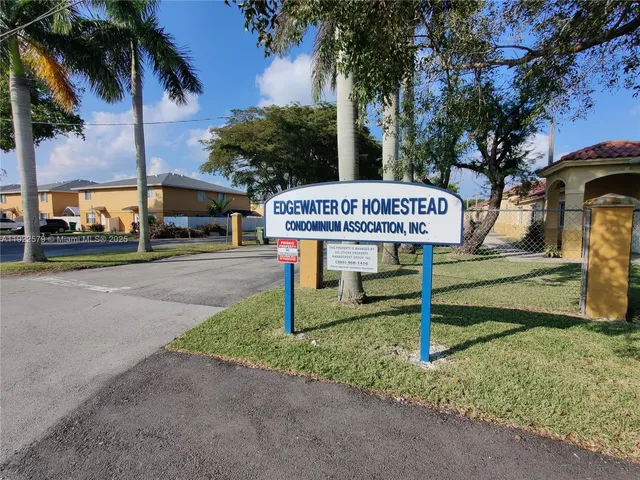 a sign on a sidewalk next to a road