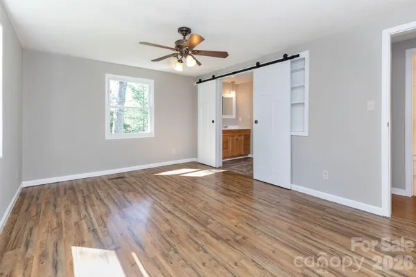 a view of empty room with wooden floor and fan