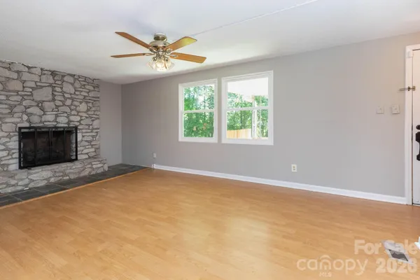 an empty room with windows and fireplace