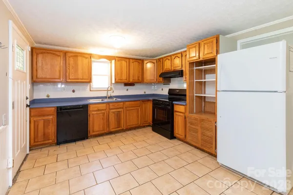 a kitchen with stainless steel appliances granite countertop a refrigerator a sink dishwasher a stove with white cabinets and wooden floor