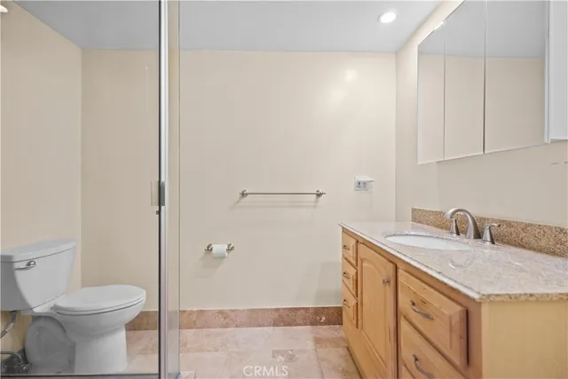 a bathroom with a granite countertop sink a toilet and a shower
