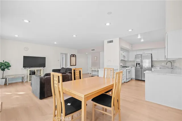 a living room with stainless steel appliances furniture a flat screen tv and kitchen view