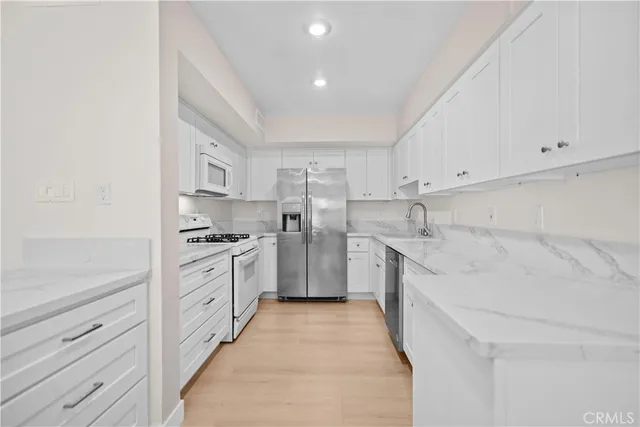 a kitchen with granite countertop a sink and white cabinets
