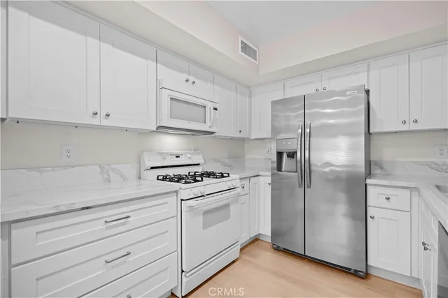 a kitchen with white cabinets and white appliances