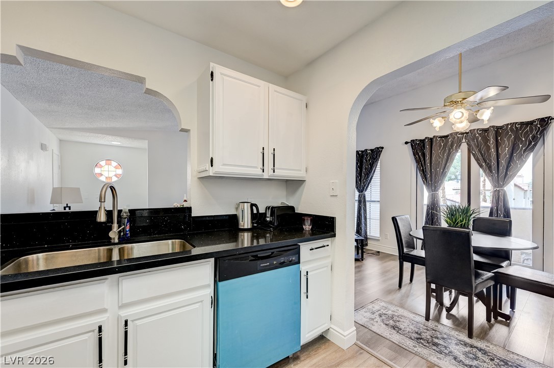 1751 East Reno Avenue, Unit 228 Las Vegas, NV 89119 - Photo 18 of 39 A well-appointed kitchen features dark countertops, white cabinetry, and an adjoining dining area with wood flooring.