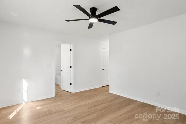 an empty room with wooden floor and a ceiling fan