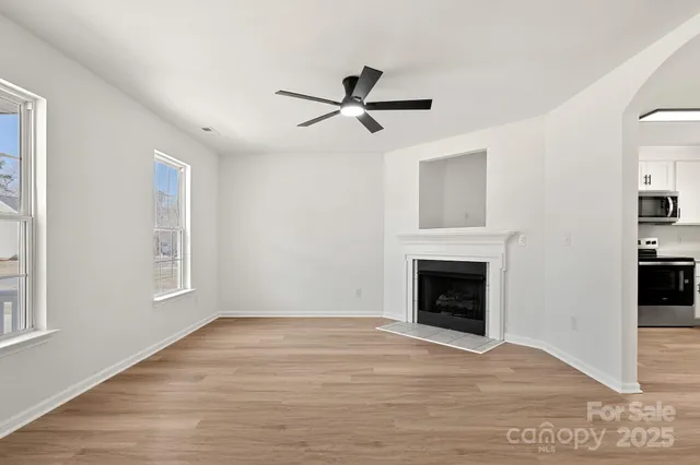 a view of empty room with wooden floor and fireplace