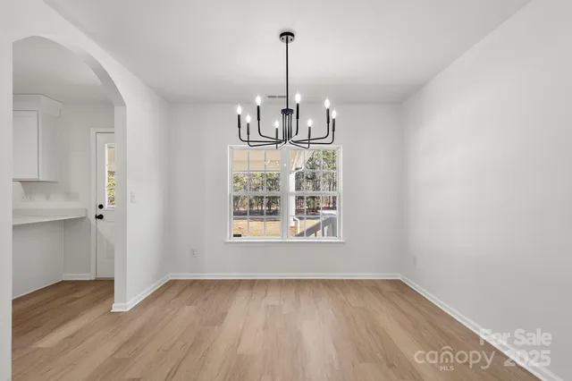 an empty room with wooden floor exposed radiator and windows