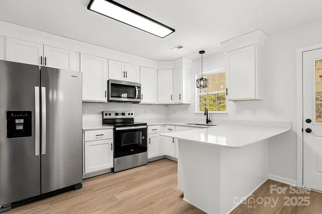 a kitchen with a sink a microwave a refrigerator and cabinets