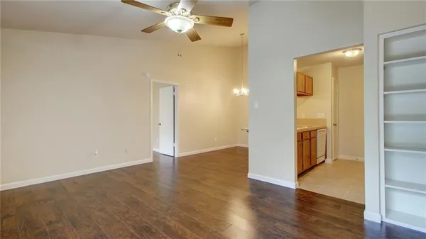an empty room with wooden floor and a ceiling fan