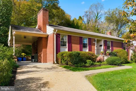 a view of a house with brick walls plants and large tree