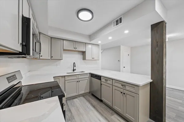 a kitchen with a sink dishwasher and white cabinets with wooden floor