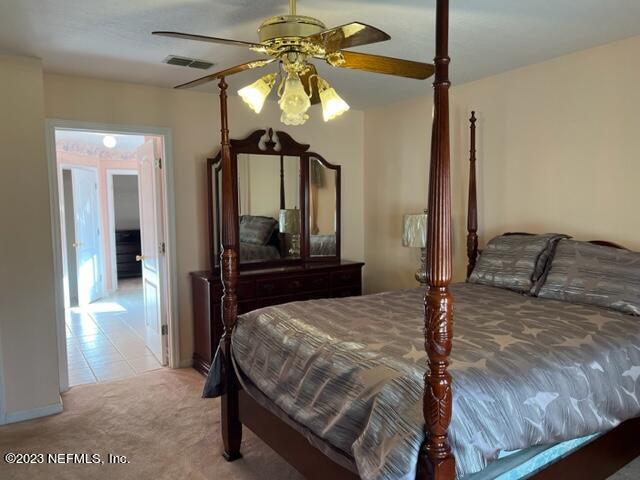 10321 Sugar Grove Road Jacksonville, FL 32221 - Photo 21 of 34 a bedroom with a bed a chandelier and dresser