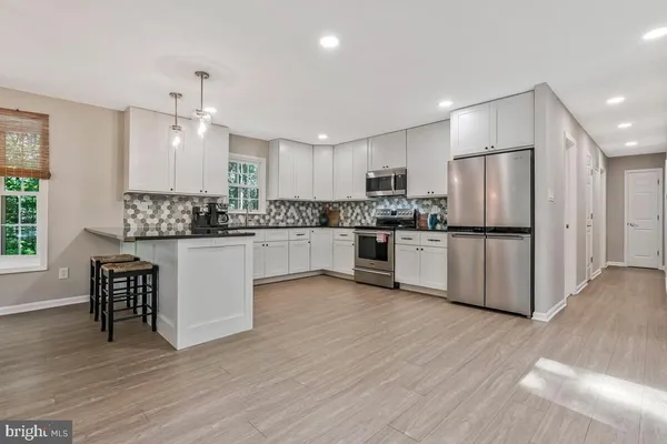 a kitchen with stainless steel appliances kitchen island granite countertop a refrigerator a stove a sink and a dining table with wooden floor