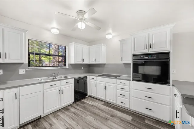 a kitchen with a stove a sink and wooden floor