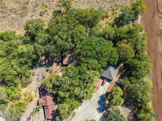 an aerial view of residential house with outdoor space and trees all around