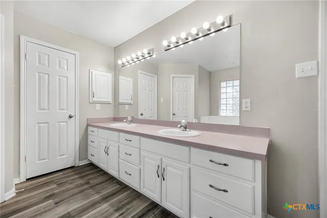 a bathroom with a granite countertop sink mirror and cabinets