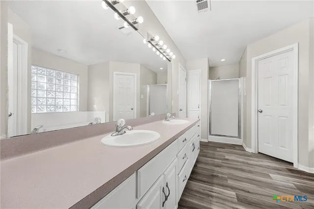 a spacious bathroom with a double vanity sink a mirror and a shower