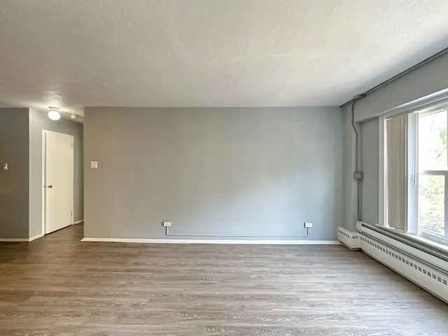 an empty room with wooden floor and window