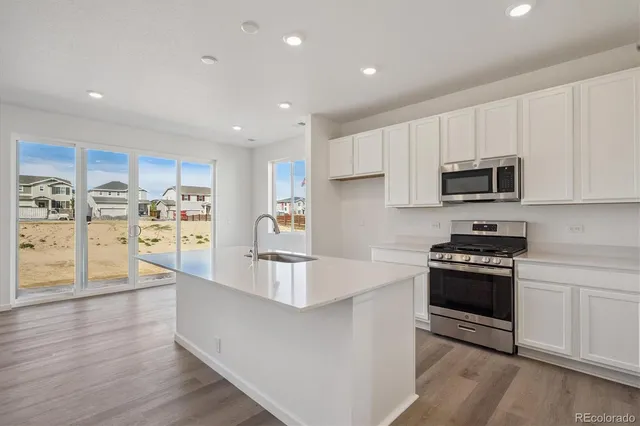 a large kitchen with stainless steel appliances granite countertop a stove a sink and a refrigerator