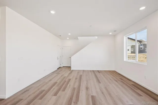 an empty room with wooden floor and windows