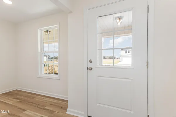 a view of kitchen and empty room with wooden floor