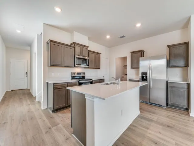 a kitchen with kitchen island a sink stove and refrigerator