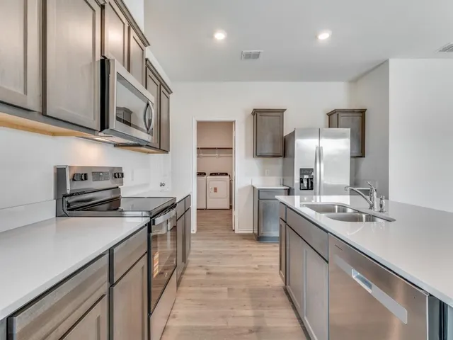 a kitchen with stainless steel appliances granite countertop a sink stove oven a refrigerator with wooden cabinets and floor