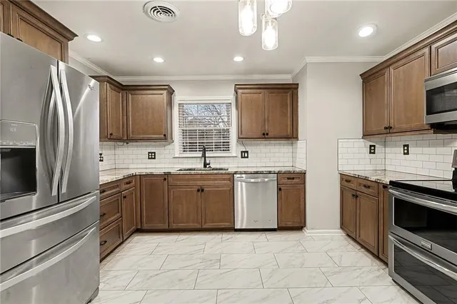 a kitchen with stainless steel appliances granite countertop a stove top oven a sink and a refrigerator