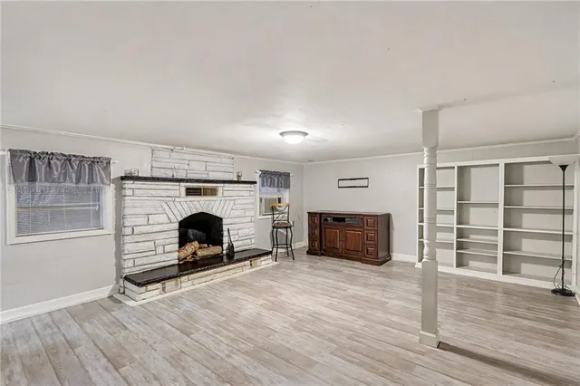 an empty room with wooden floor fireplace and windows