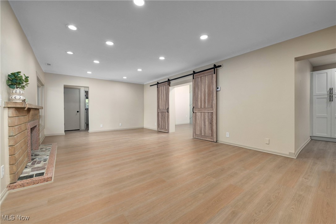 433 Chestnut Road Independence, OH 44131 - Photo 7 of 50 Unfurnished living room featuring recessed lighting, a barn door, light wood-style flooring, and a brick fireplace