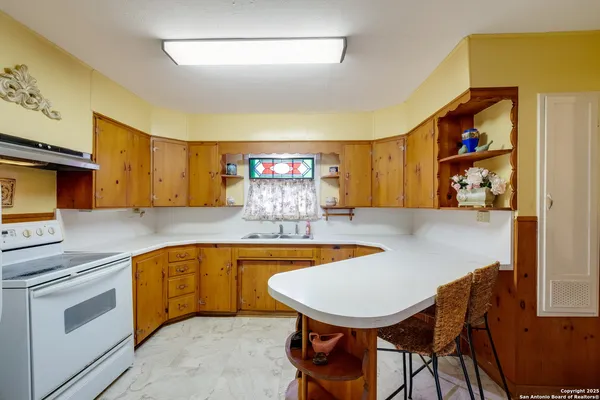 a kitchen with stainless steel appliances granite countertop a sink and chairs