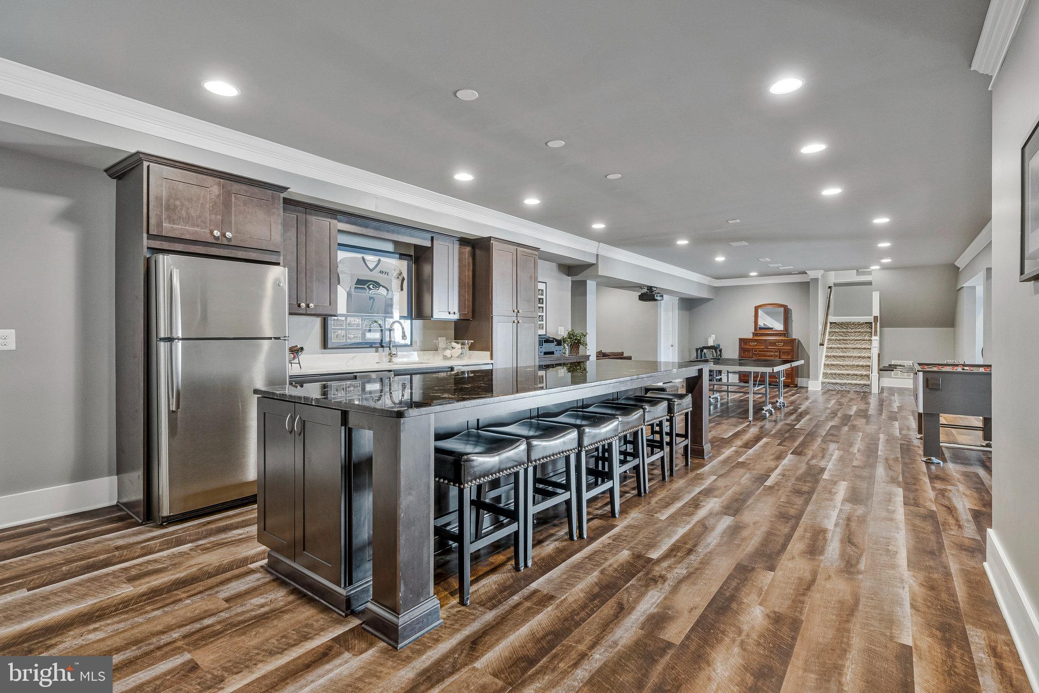 41865 Scotchbridge Place Ashburn, VA 20148 - Photo 67 of 93 a kitchen with stainless steel appliances kitchen island granite countertop a table chairs in it and wooden floors