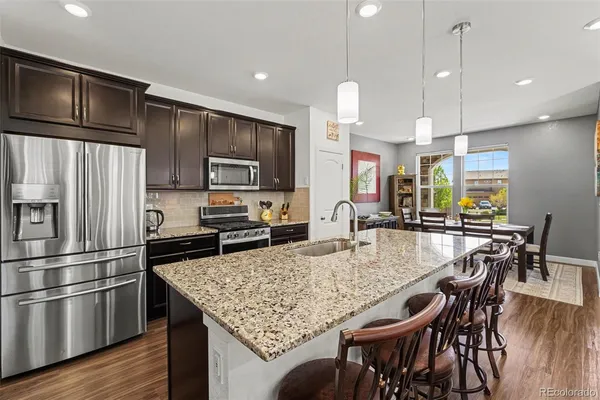a kitchen with stainless steel appliances granite countertop a kitchen island hardwood floor and chairs